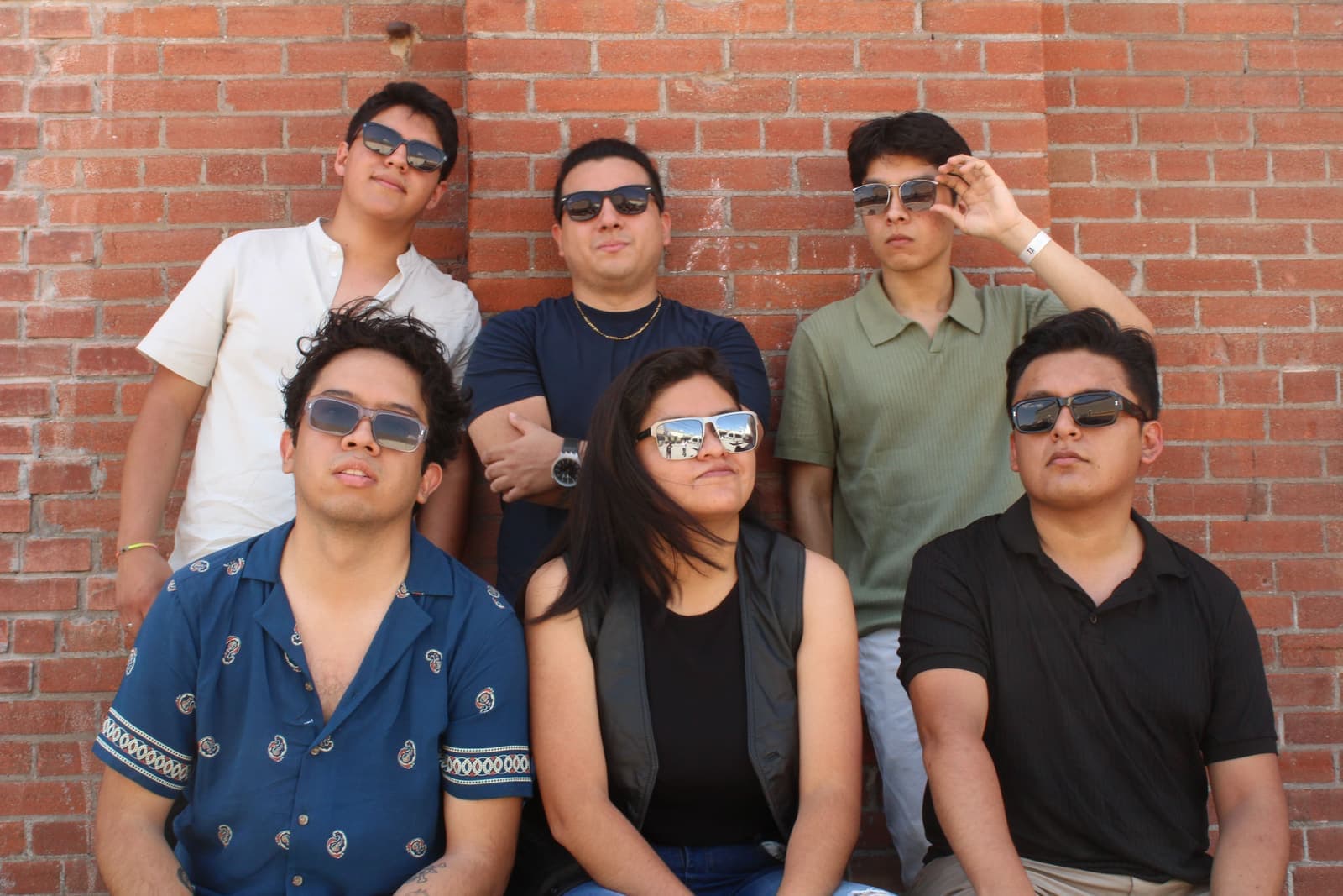 Los seis integrantes de Band der Waals frente a un muro de ladrillo, con lentes de sol